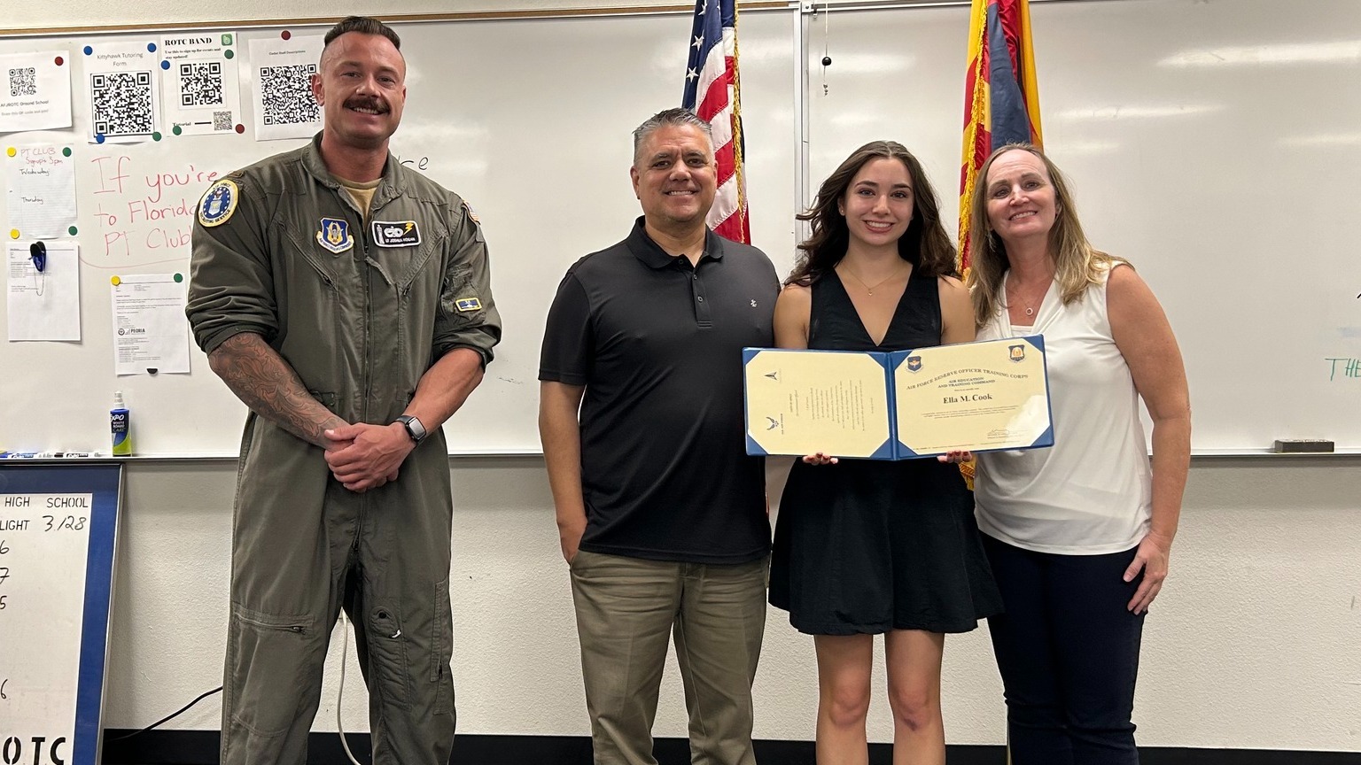 Student holding up certificate with parents and officer