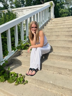 A woman in a white dress sits gracefully on steps, exuding elegance and tranquility in her serene surroundings.