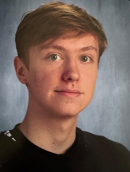 A young man wearing a black shirt, showcasing his striking green eyes, exuding confidence and style.
