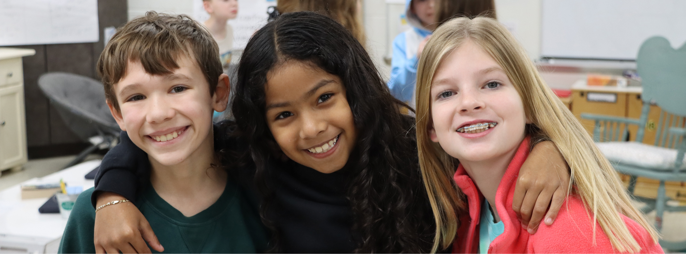 three students smiling at the camera with their arms around one another