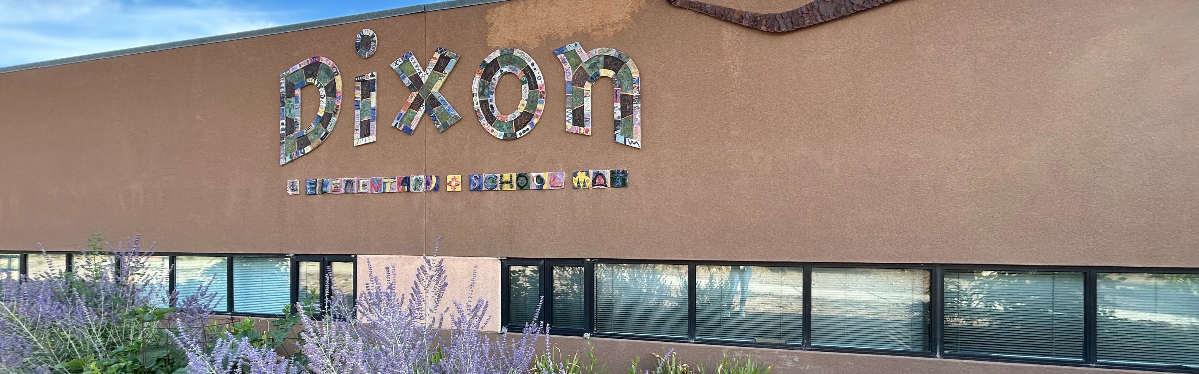 A building with the word Dixon in white letters. There are plants and flowers in the foreground.