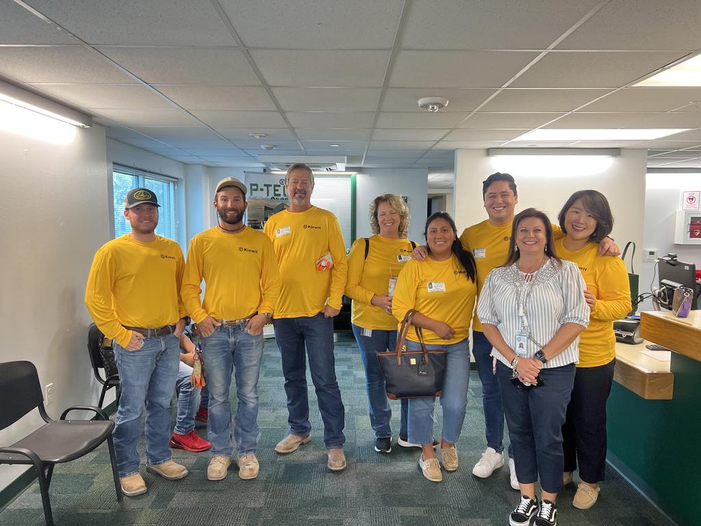 A diverse group of individuals in yellow shirts collaborating in a modern office environment.