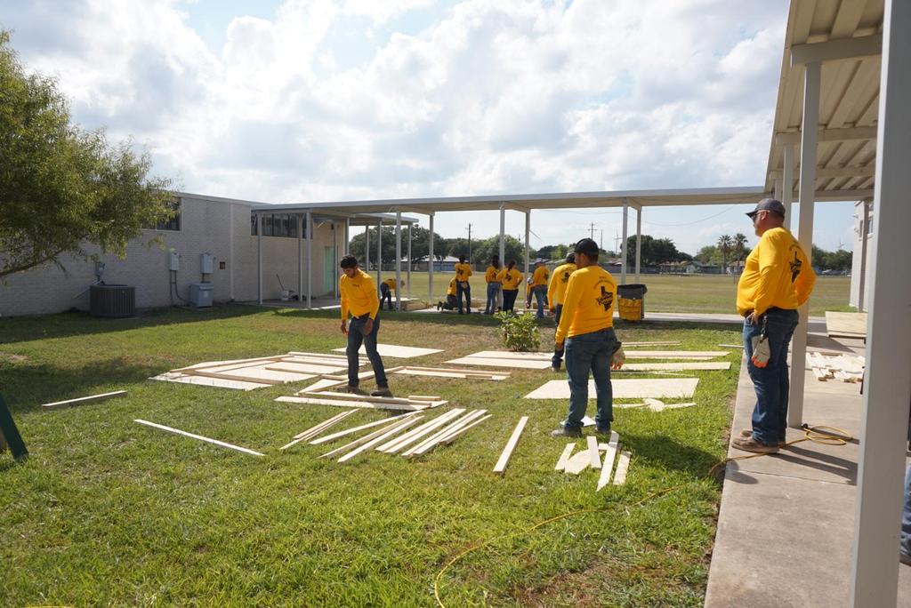 A diverse group of individuals in yellow shirts collaborating on a project, showcasing teamwork and creativity.