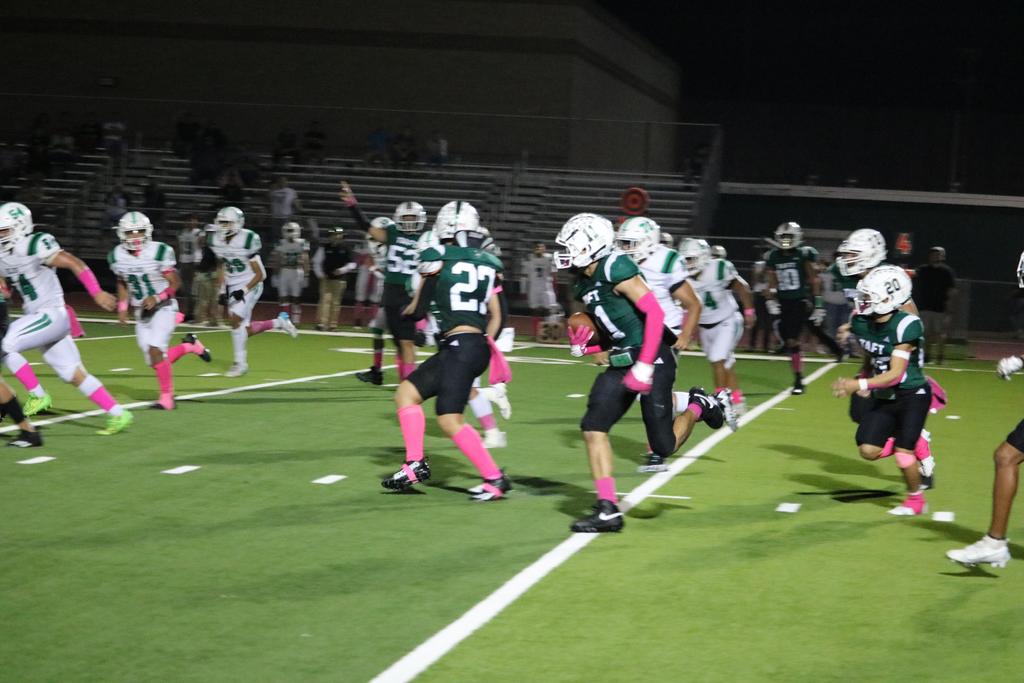 A group of football players sprinting across the field during a match, showcasing teamwork and athleticism.