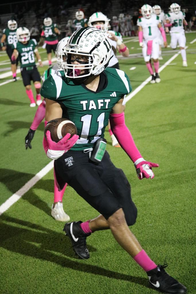 A football player sprinting down the field, skillfully carrying the ball towards the goal line.