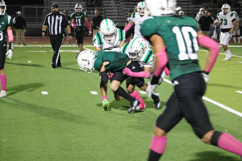 A football player is being tackled by an opposing player during a game, showcasing the intensity of the sport.
