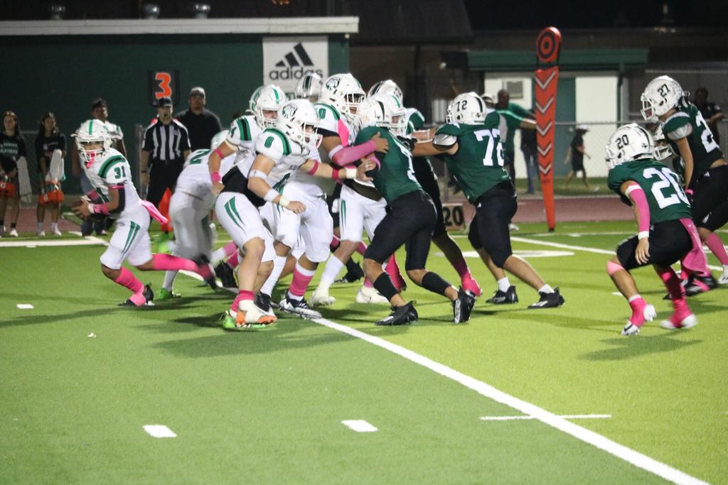 A dynamic football game scene featuring players actively running and blocking each other on the field.