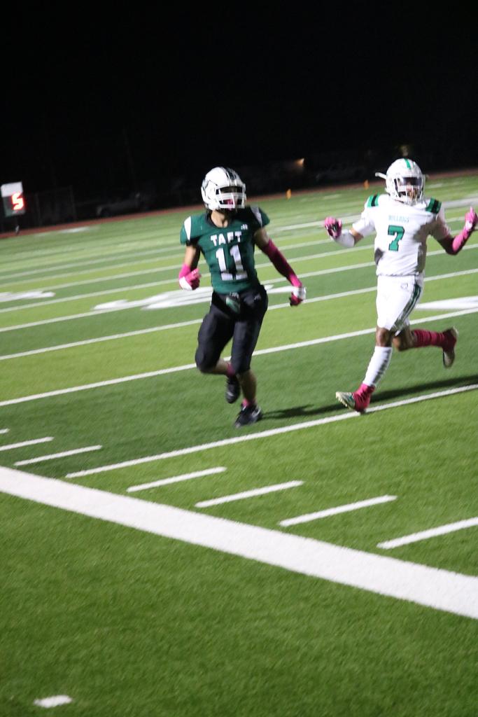A football player sprinting across the field while gripping the ball tightly in preparation for a play.