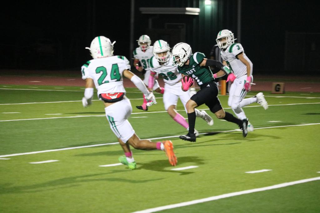 A football player sprinting down the field, skillfully carrying the ball towards the goal line.