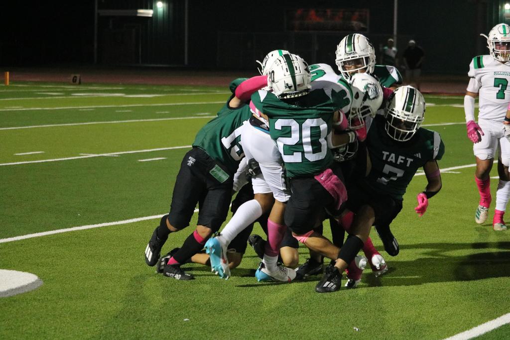 A group of football players competes energetically to gain possession of the ball on the field.