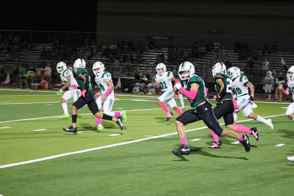 A group of football players sprinting across the field during a match, showcasing teamwork and athleticism.