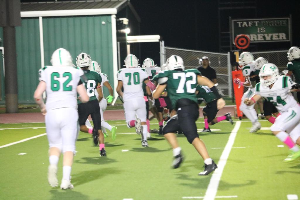 A group of football players sprinting across the field during an intense match, showcasing teamwork and athleticism.