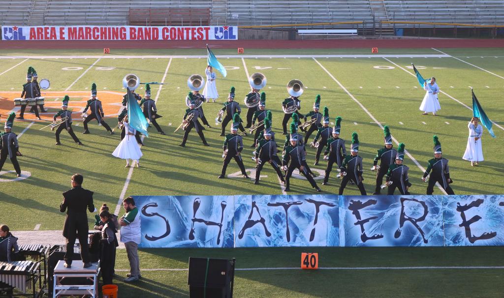 A marching band performs on a field, proudly displaying a banner that reads "Shatters" in bold letters.
