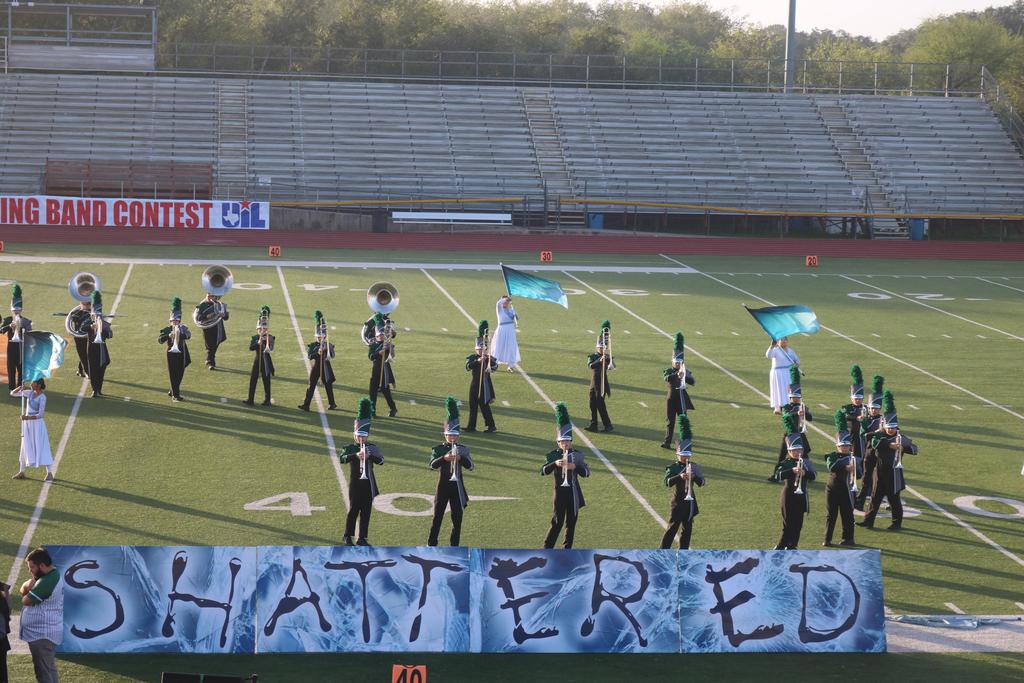 A marching band performs on the field, proudly displaying a banner that reads "Shattered" in bold letters.