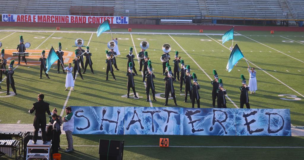 A marching band parades with a vibrant banner displaying the word "shattered," showcasing their musical performance.