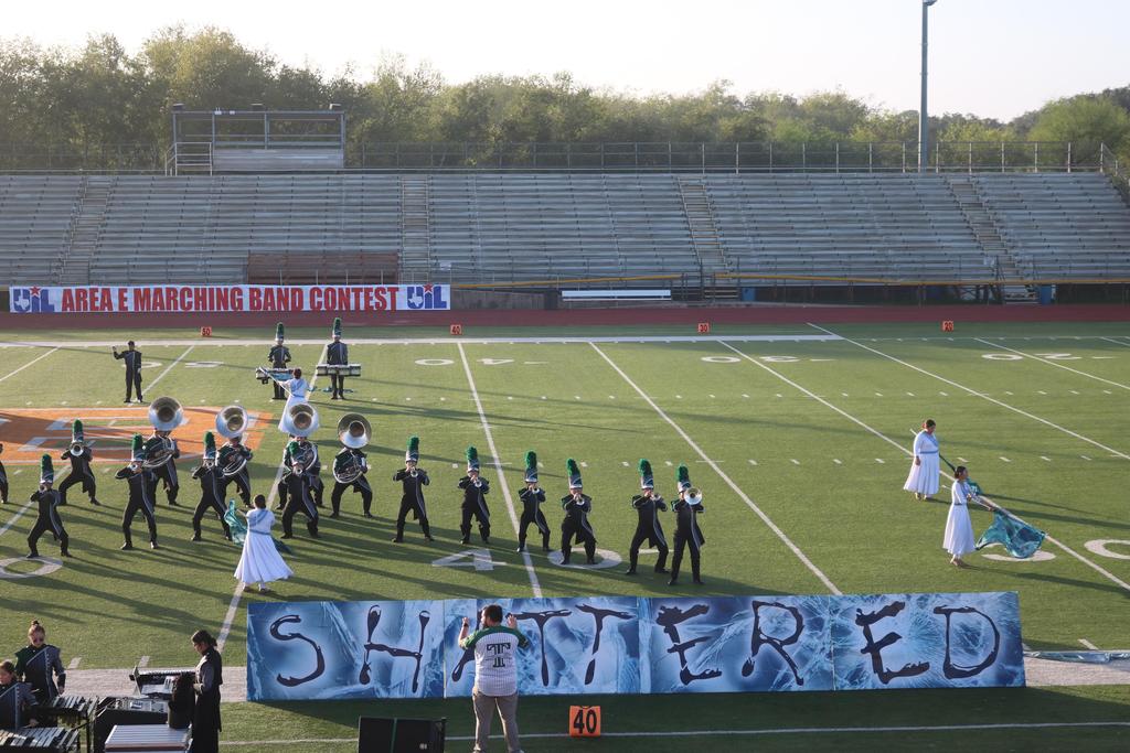 A marching band performs on the field, proudly displaying a banner that reads "Shattered" in bold letters.