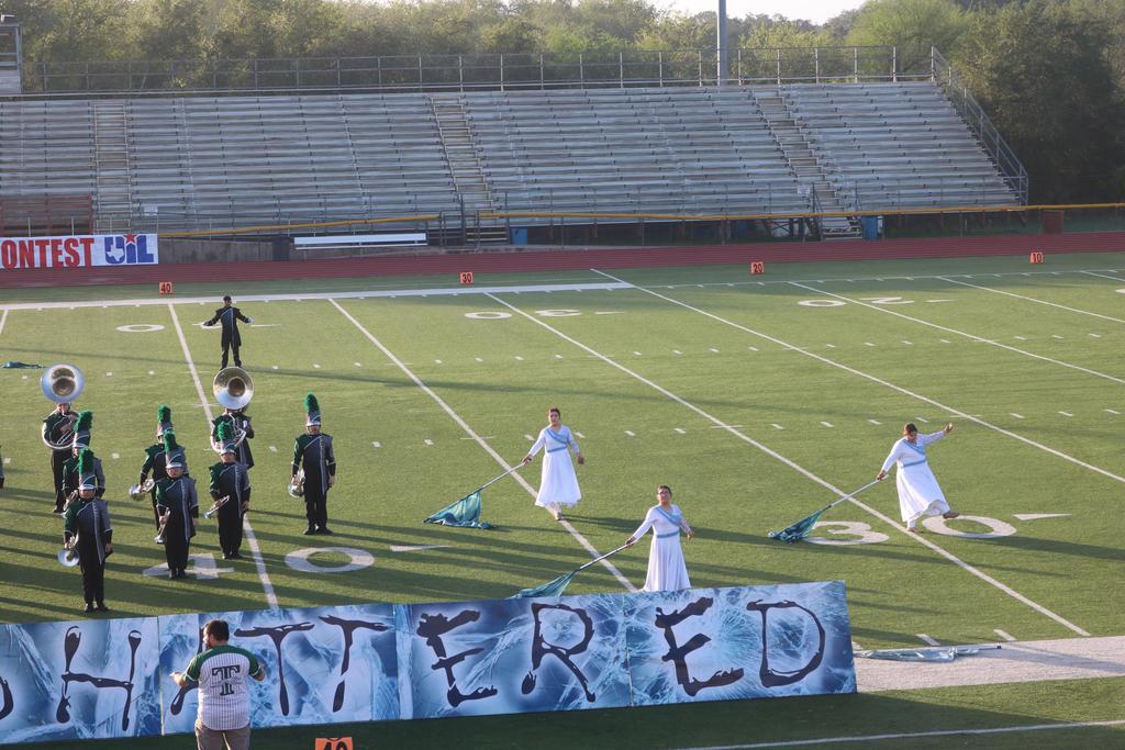 A marching band performs on the field, proudly displaying a banner that reads "Shattered" in bold letters.