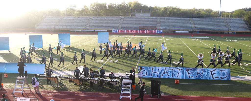 A band energetically performing on a football field, surrounded by cheering fans and vibrant stage lights.