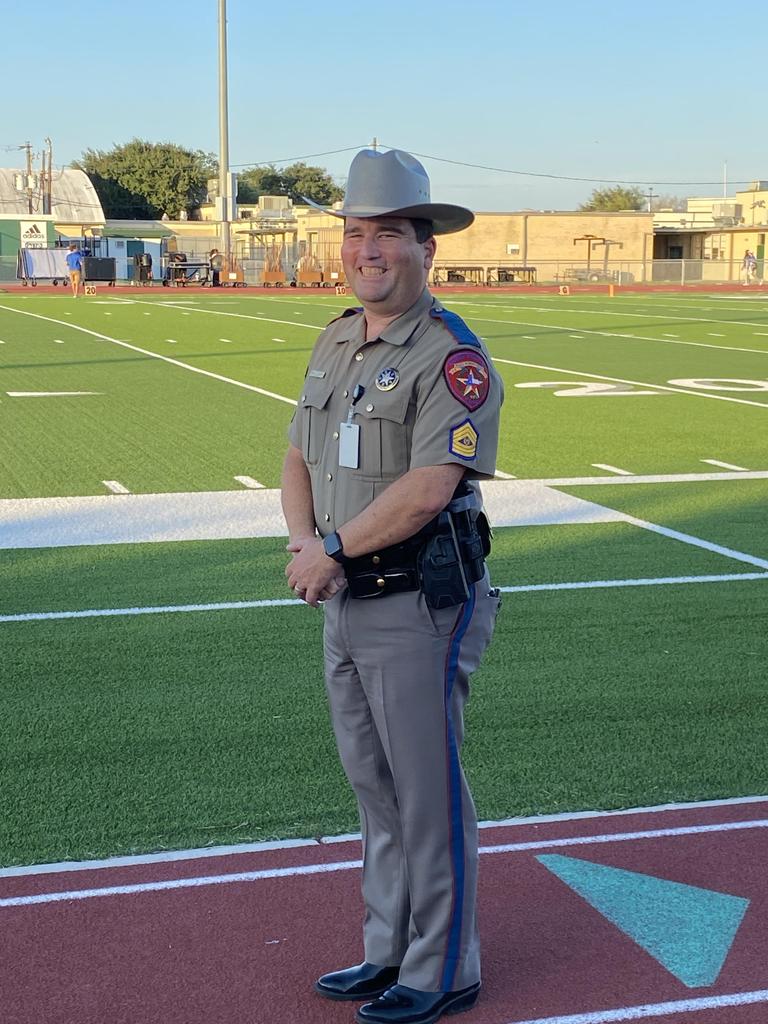 A man in uniform stands confidently on a football field, ready for action under the bright stadium lights.