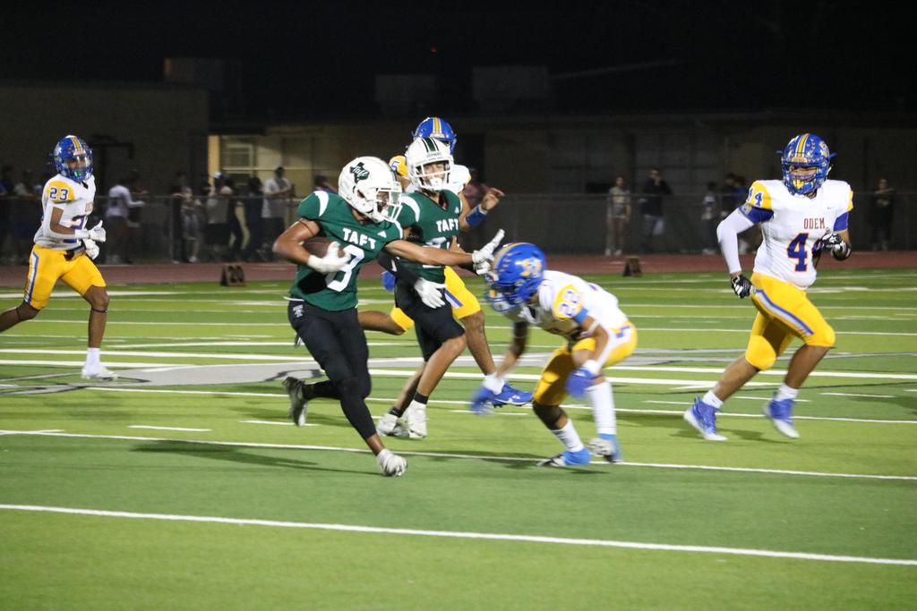 A football player sprinting across the field while gripping the ball tightly, showcasing agility and determination.