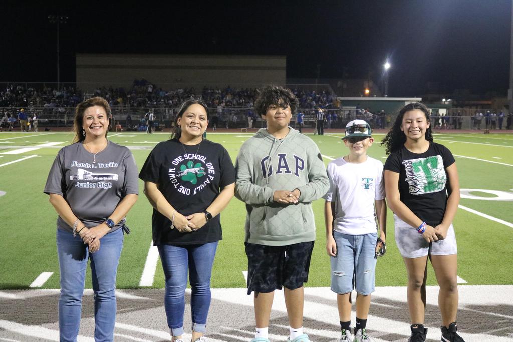 A diverse group of individuals gathered on a football field, showcasing teamwork and camaraderie in a vibrant outdoor setting.