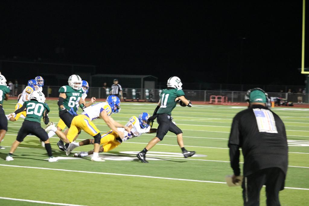 A dynamic football game scene featuring players in motion and a focused coach on the sidelines.