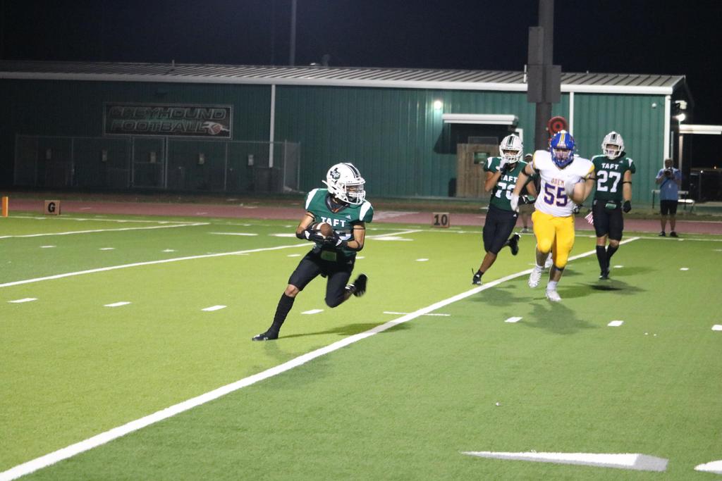 A football player sprinting across the field under the night sky, illuminated by stadium lights.