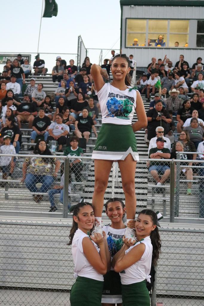 A cheerleader balances on another cheerleader's shoulders during a performance, showcasing teamwork and athleticism.