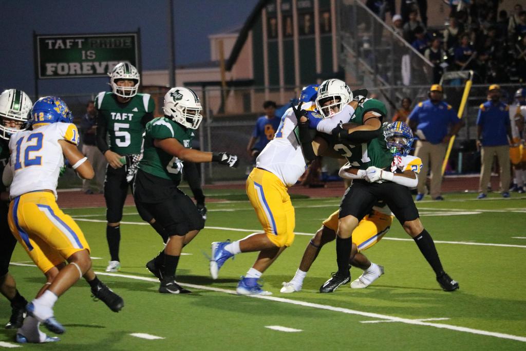 A football player competes for possession of the ball amidst a group of opposing players on the field.