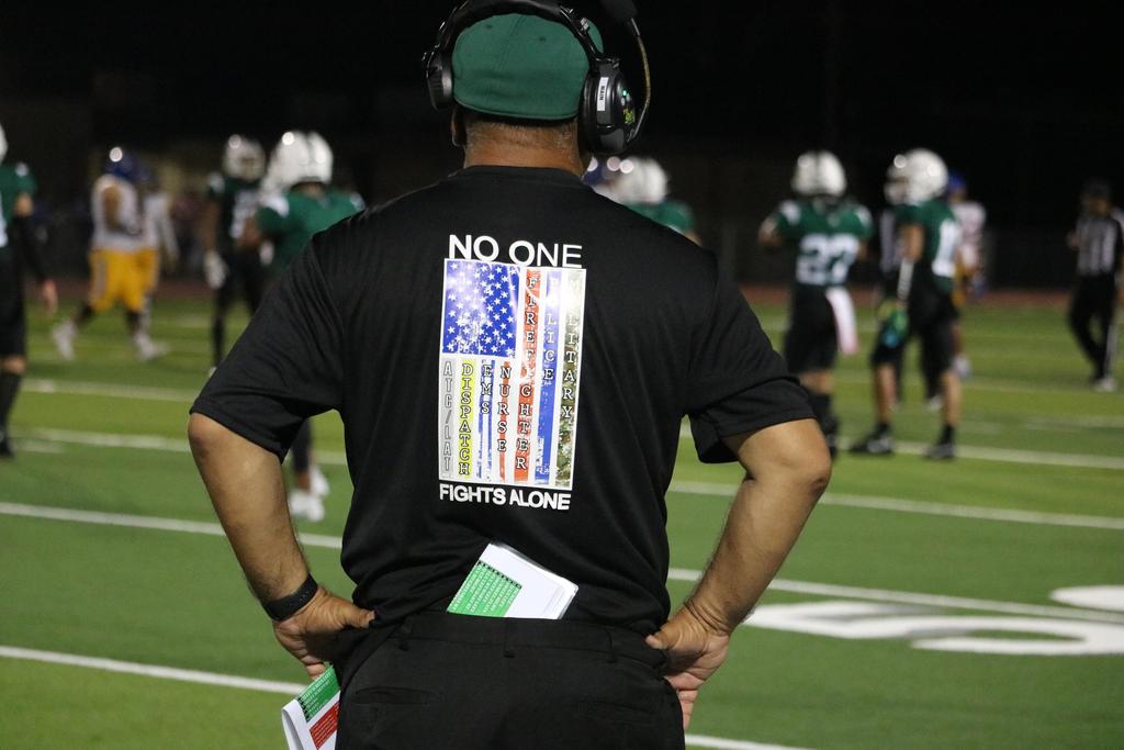 A football coach proudly wearing a shirt adorned with the American flag, symbolizing patriotism and team spirit.
