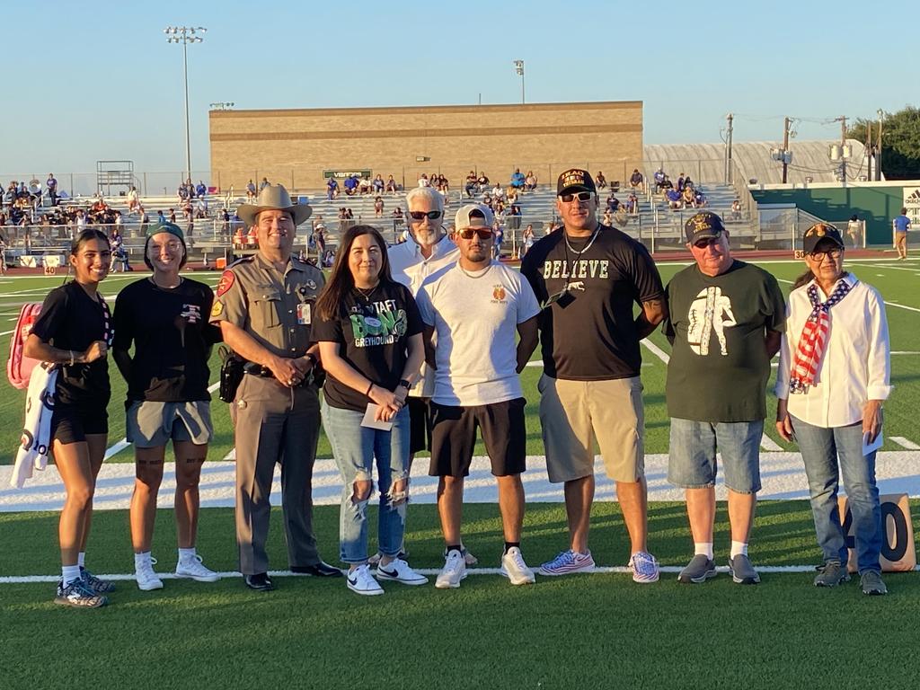 A diverse group of individuals gathered on a football field, showcasing teamwork and camaraderie in a vibrant outdoor setting.
