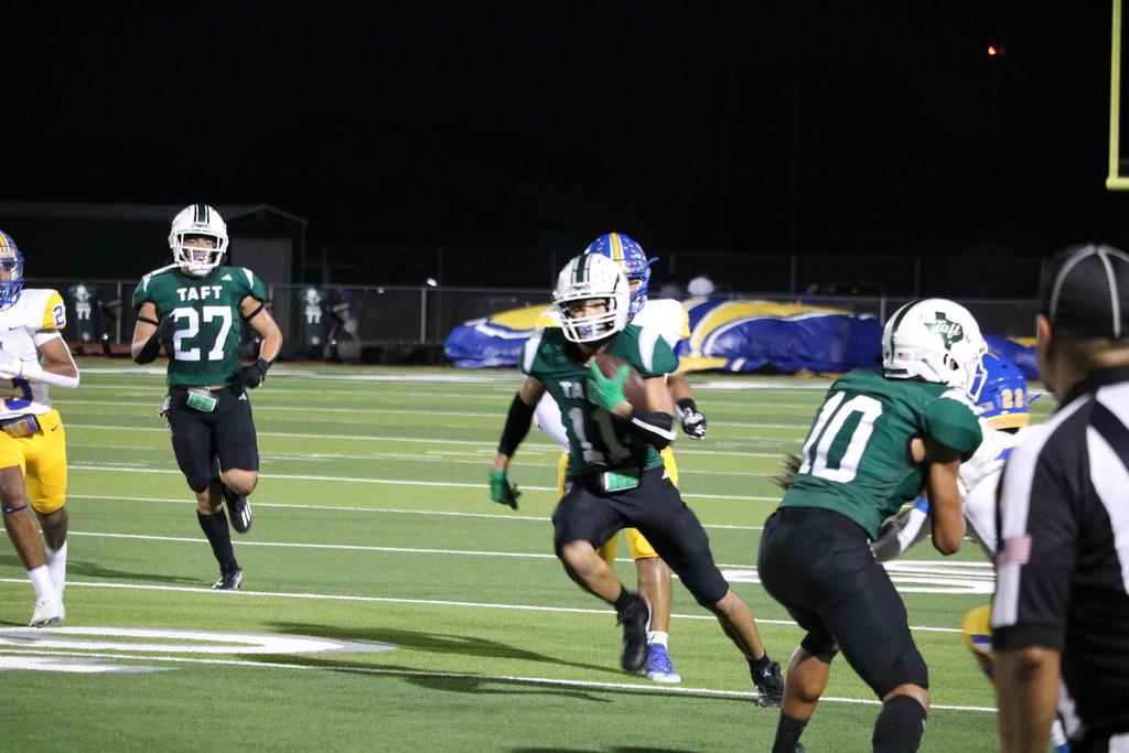 A football player sprinting down the field, skillfully carrying the ball towards the goal line.
