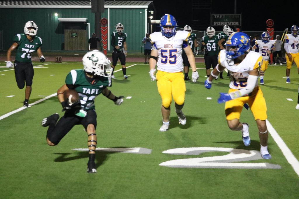 A football player sprinting while holding the ball high above his head during a game.
