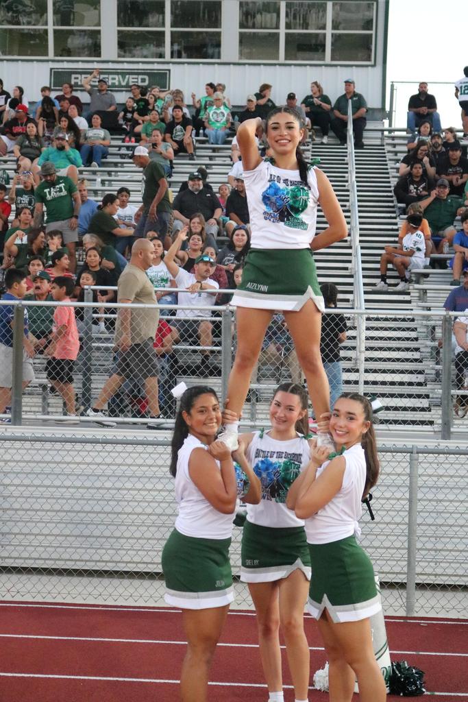 A cheerleader performs a stunt by standing on the shoulders of another cheerleader during a spirited routine.