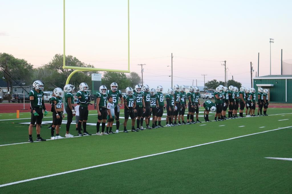 A group of football players stands together on the field, showcasing teamwork and athleticism in their uniforms.