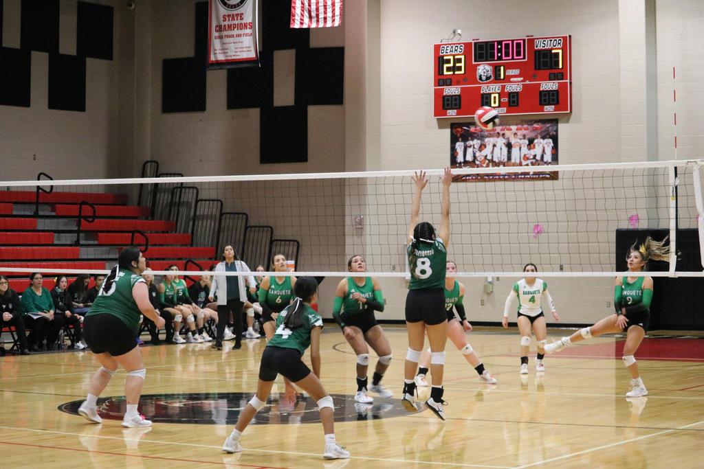 A volleyball player extends their arm to hit the ball during a competitive match on the court.