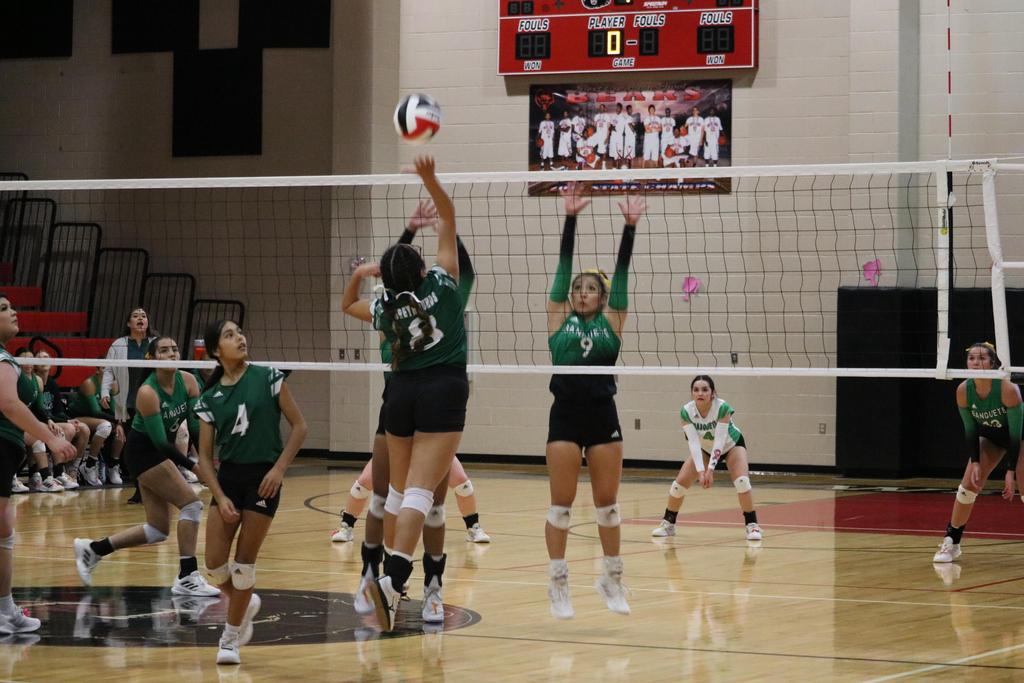 A volleyball player extends their arm to hit the ball during a competitive match on the court.