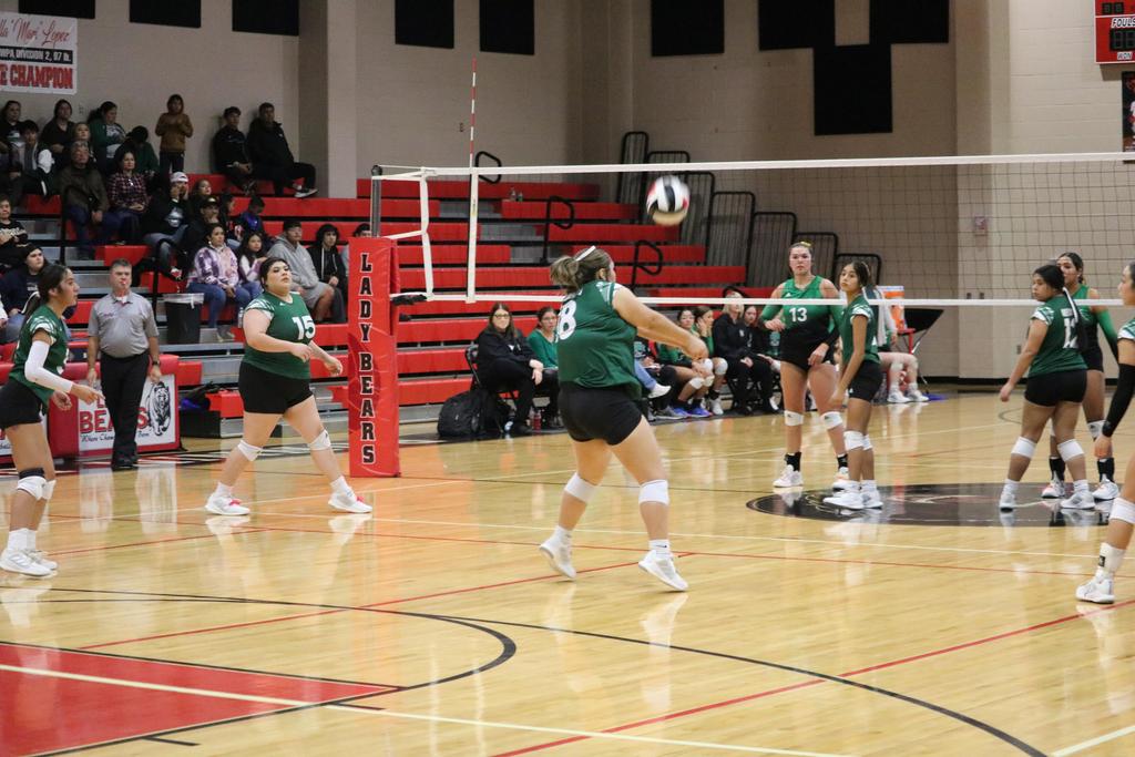 A group of girls engaged in a lively volleyball game on a court, showcasing teamwork and athleticism.