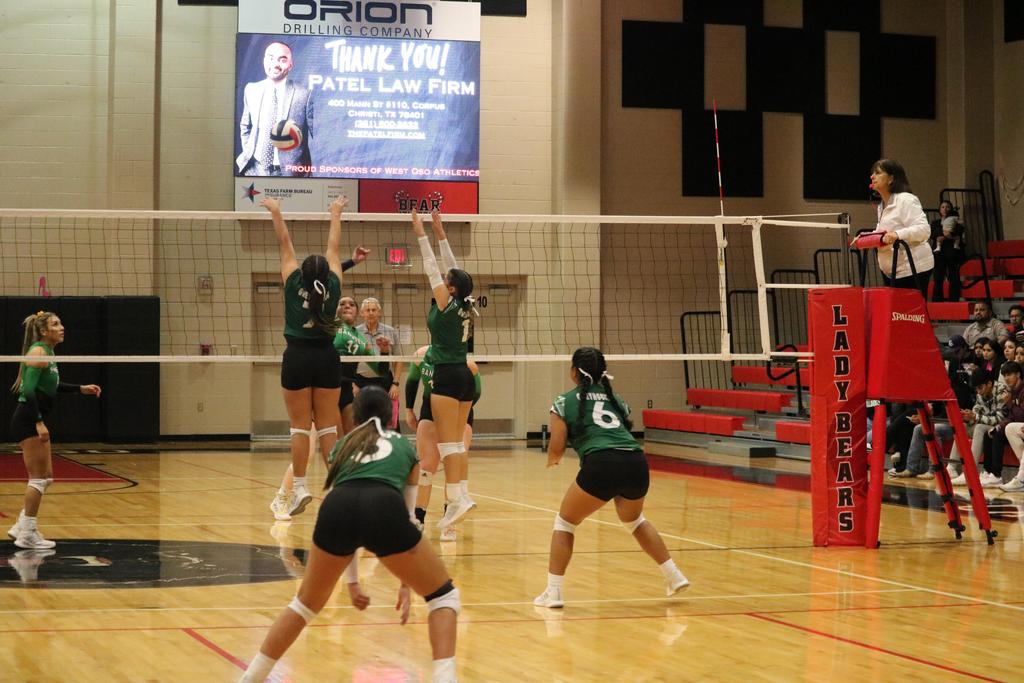 A volleyball team competes energetically in a gymnasium, showcasing teamwork and athleticism during a match.