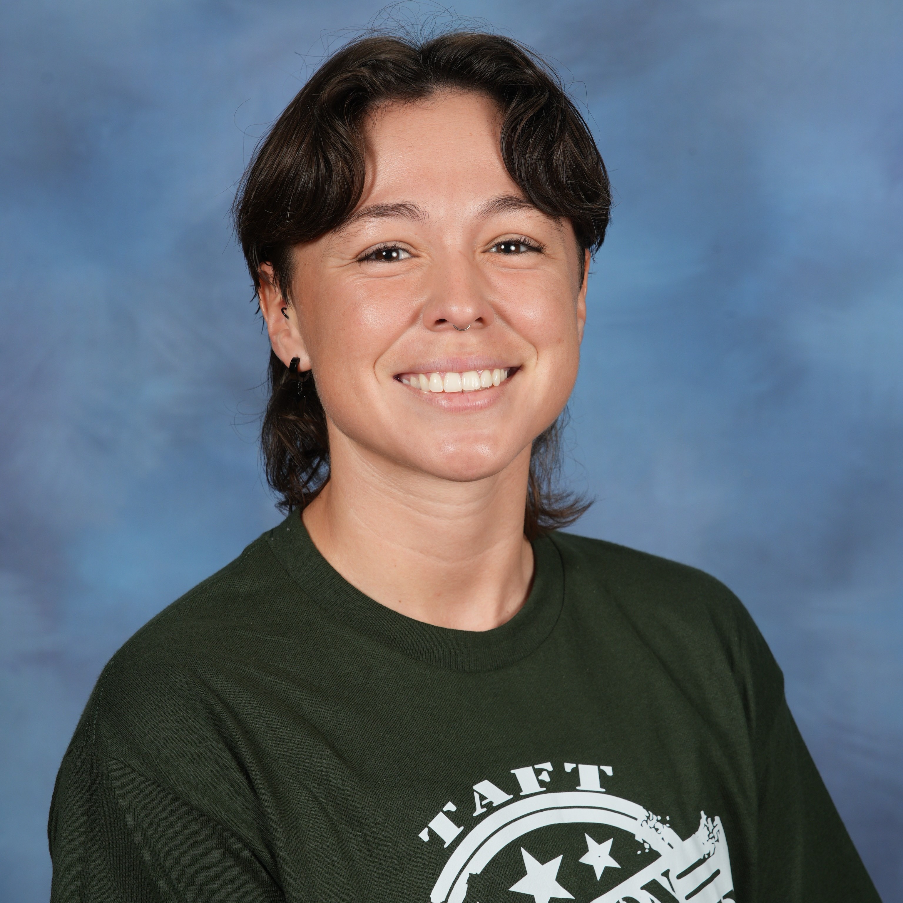 A woman wearing a green shirt and jeans stands confidently against a vibrant blue background.