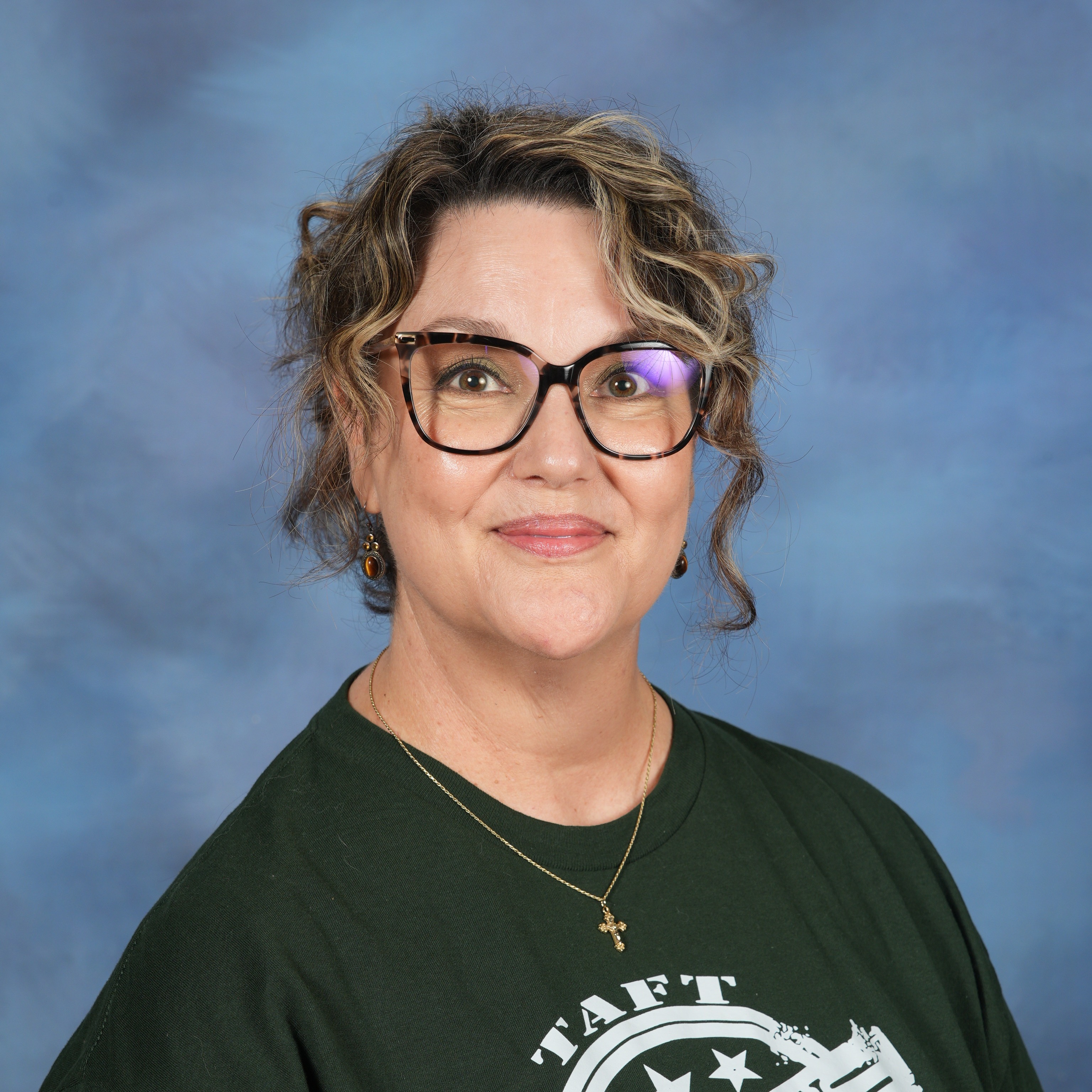 A woman with glasses wearing a green shirt, smiling and looking confidently at the camera.