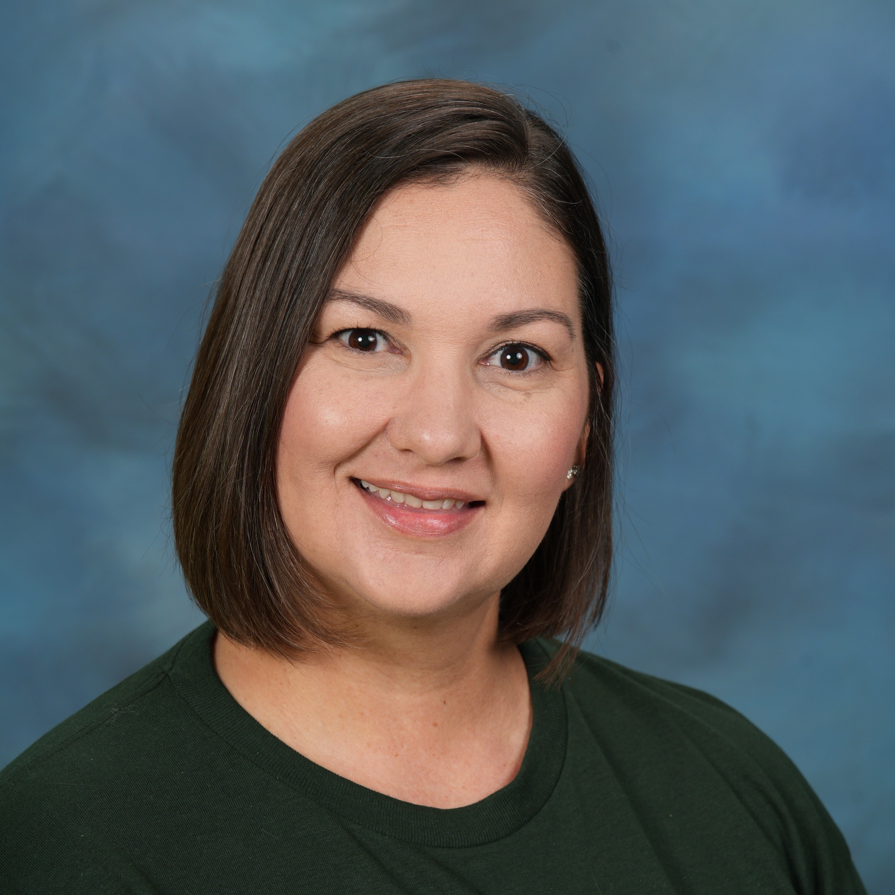 A woman wearing a green shirt stands confidently against a vibrant blue background.