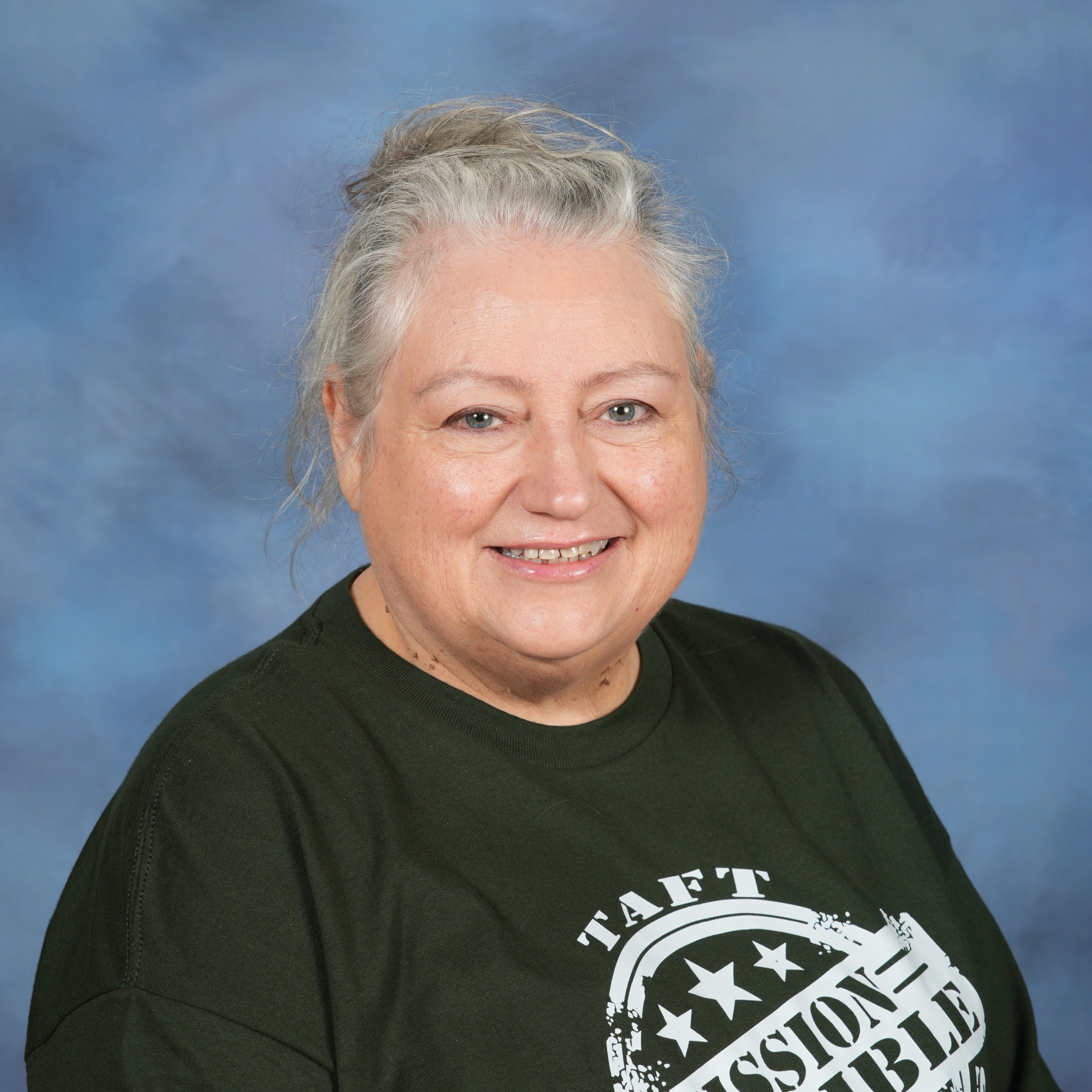 A woman wearing a green shirt stands confidently against a vibrant blue background.