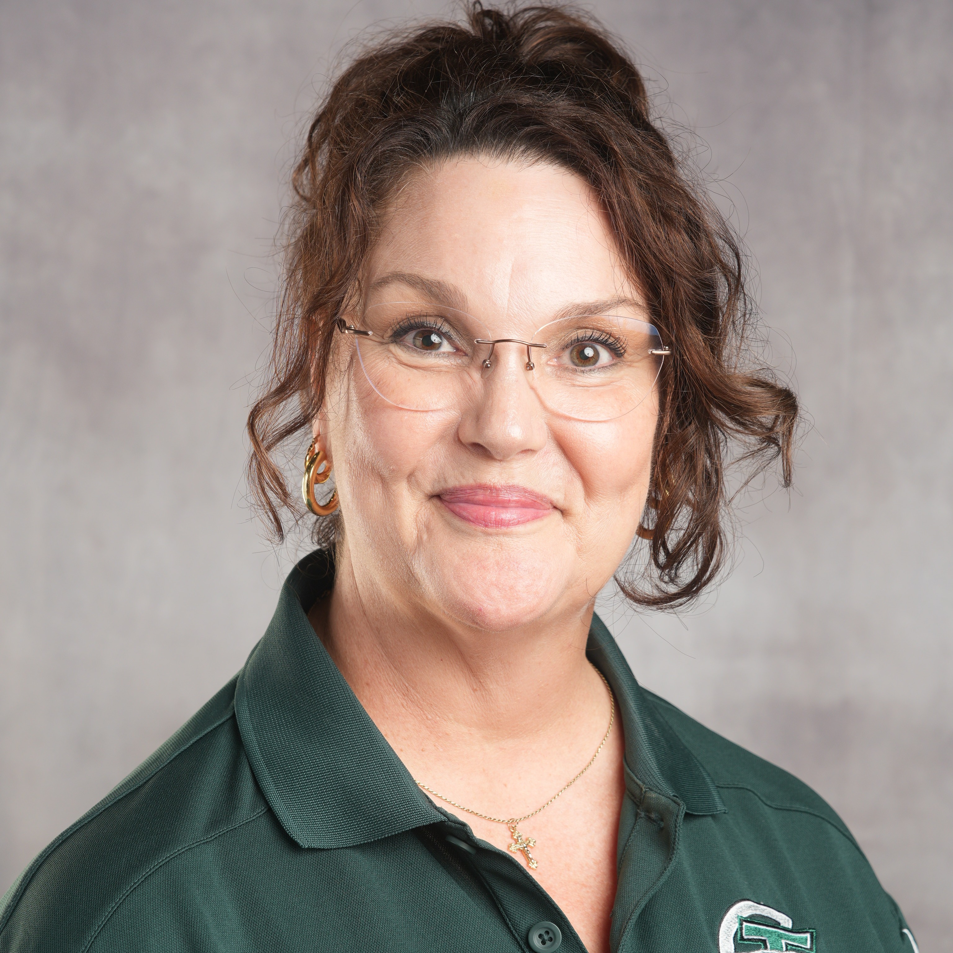 A woman with glasses wearing a green shirt, smiling and looking confidently at the camera.