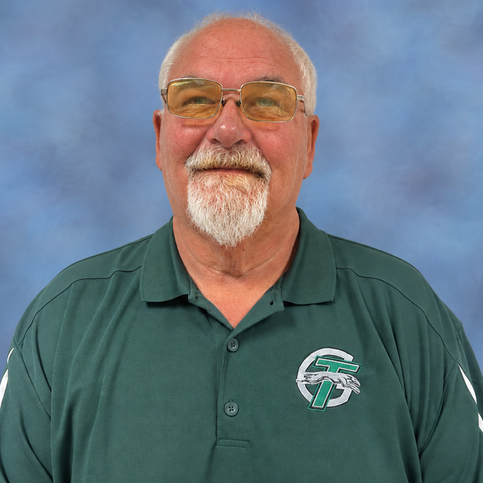 A man wearing glasses and a green shirt, looking thoughtfully into the distance.