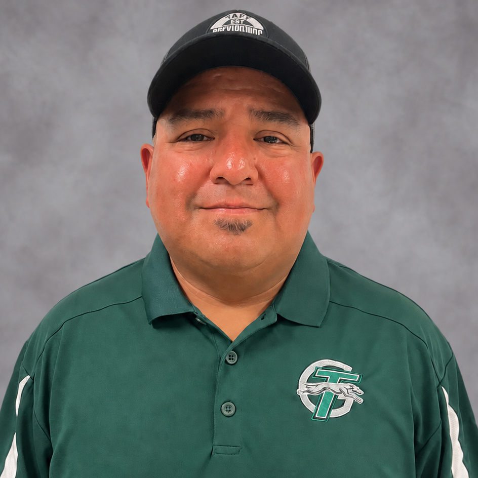 A man wearing a green shirt and a black hat stands confidently, showcasing a casual yet stylish appearance.