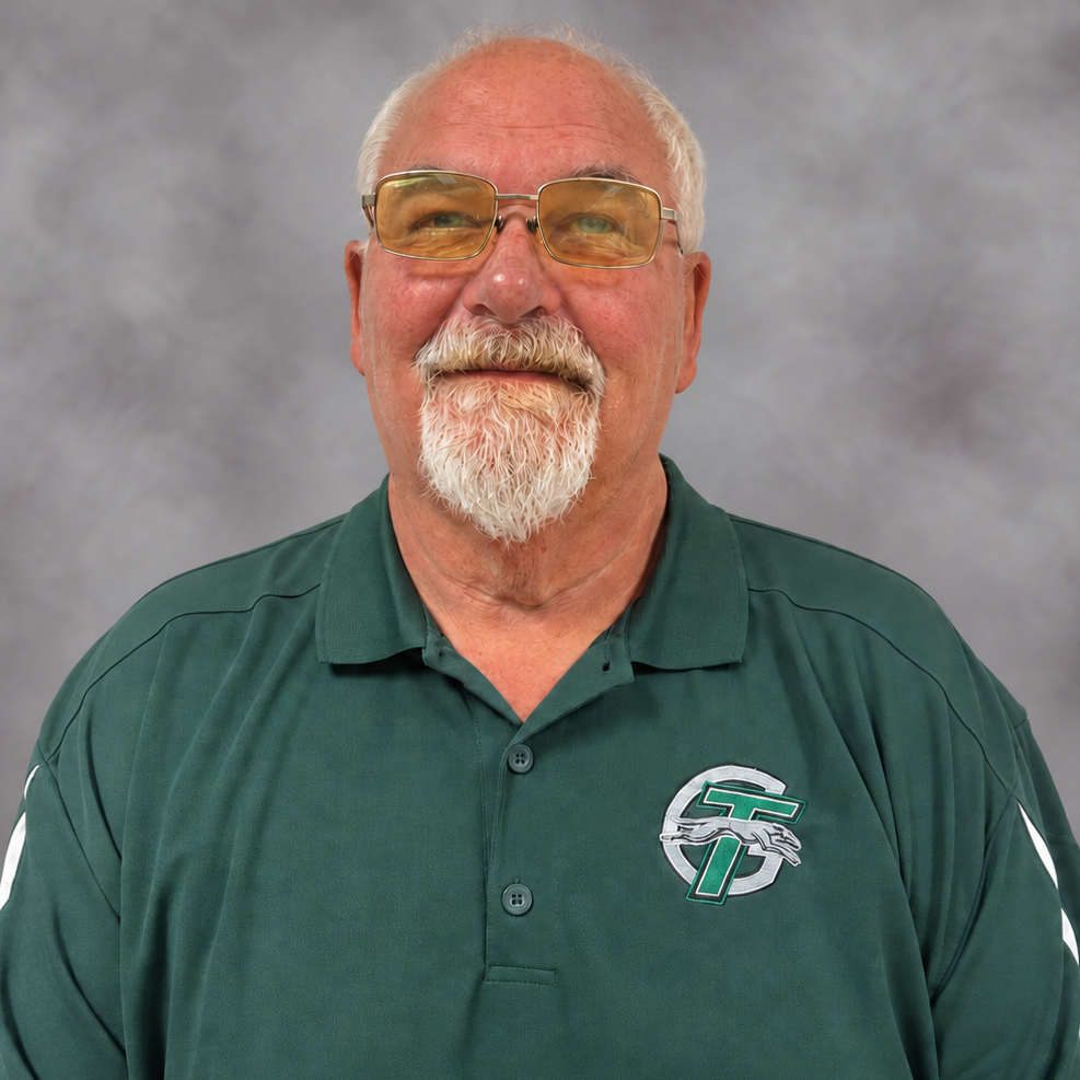 A man wearing glasses and a green shirt, looking thoughtfully into the distance.