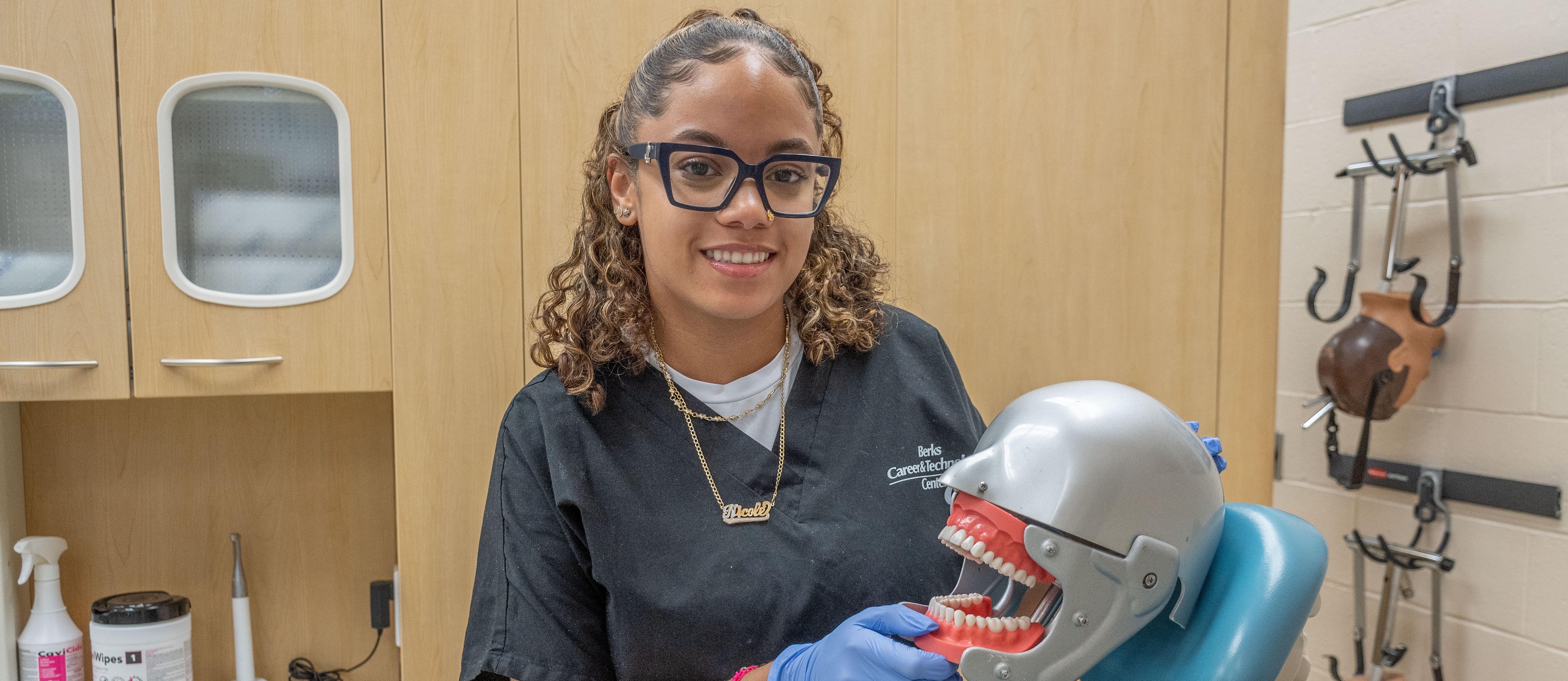 A female student examines a set of teeth on a mannequin