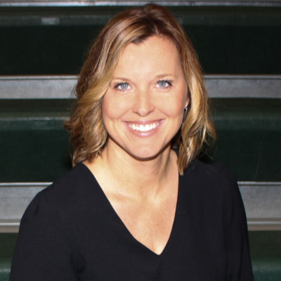 A woman wearing a black shirt smiles warmly at the camera, exuding confidence and positivity.