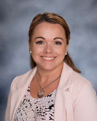 A woman wearing a pink blazer over a white shirt, exuding confidence and professionalism in her attire.